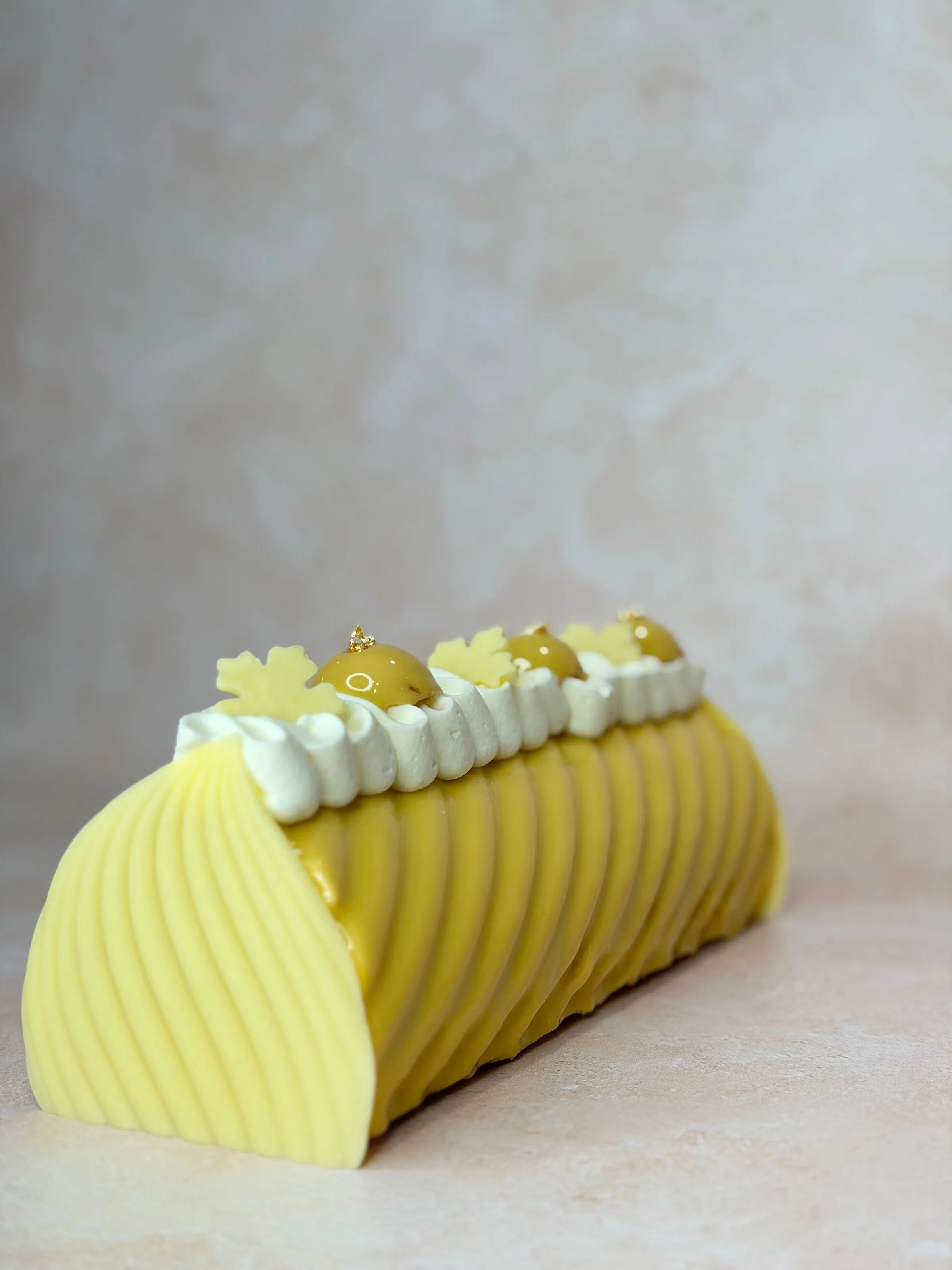 Entremets roulé jaune, décor poché et perles dorées