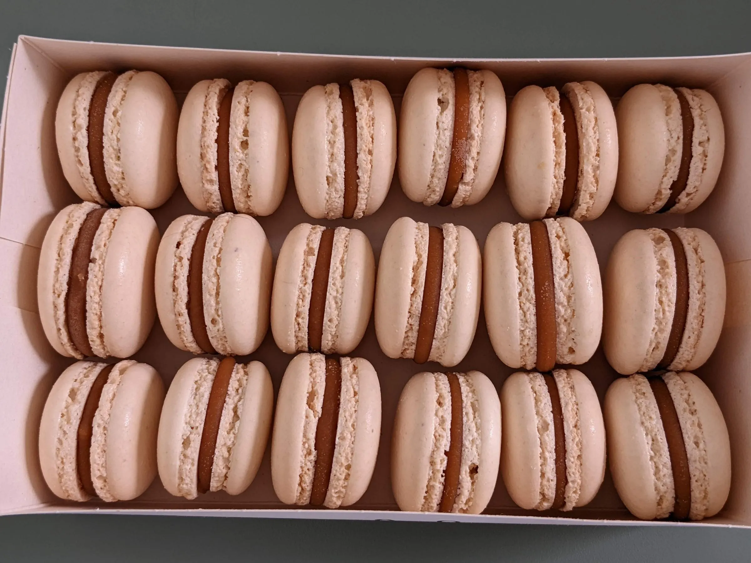 Assortiment de macarons artisanaux en boîte, tons rosés